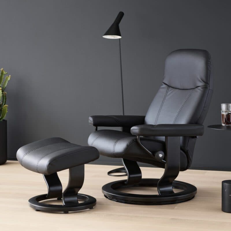 Stressless Consul Sessel mit Hocker in Leder Batick Black mit Gestell in Schwarz.