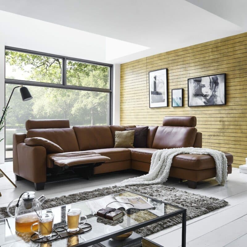 Couchliebe „Hamburg” Polsterecke mit Echtlederbezug in Credo Brandy und Füßen in Holz Eiche maron Wohnbeispiel.