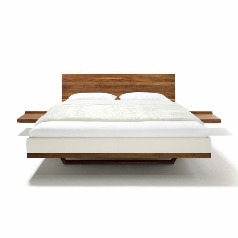 Team 7 „Riletto“ Bett in Nussbaum mit Lederbezug Origon in Weiß inklusive Konsole in frontaler Ansicht.