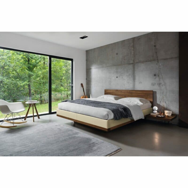 Team 7 „Riletto“ Bett in Nussbaum mit Lederbezug Origon in Weiß inklusive Konsole im Milieu.