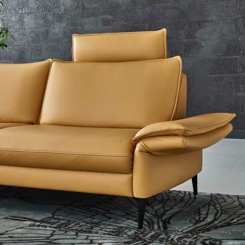 Couchliebe Houston Elementgruppe mit Lederbezug in Curry und Ottomane links als Wohnbeispiel mit Detailansicht .