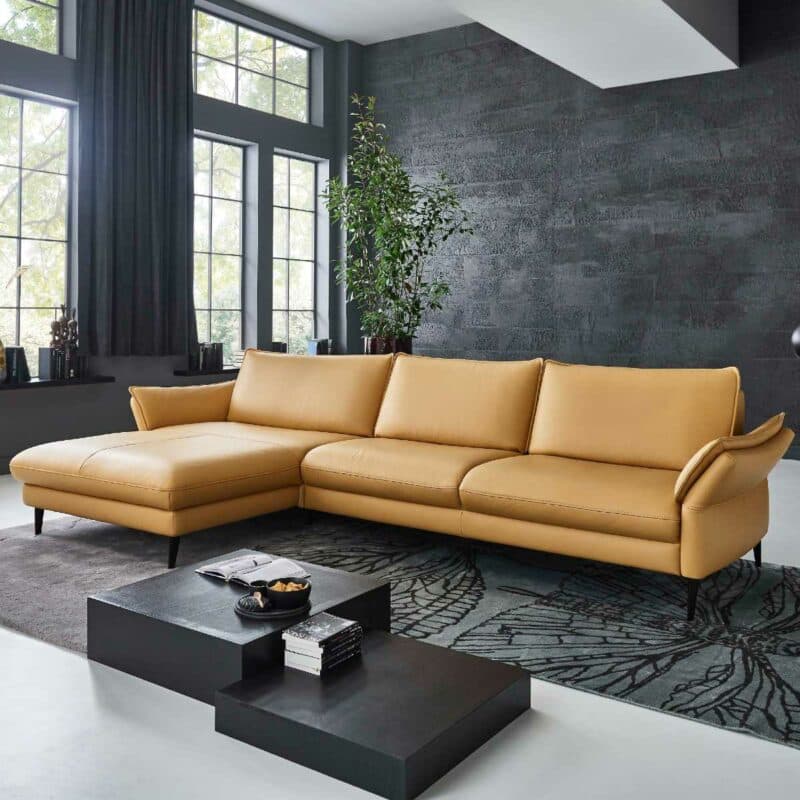 Couchliebe Houston Elementgruppe mit Lederbezug in Curry und Ottomane links als Wohnbeispiel.