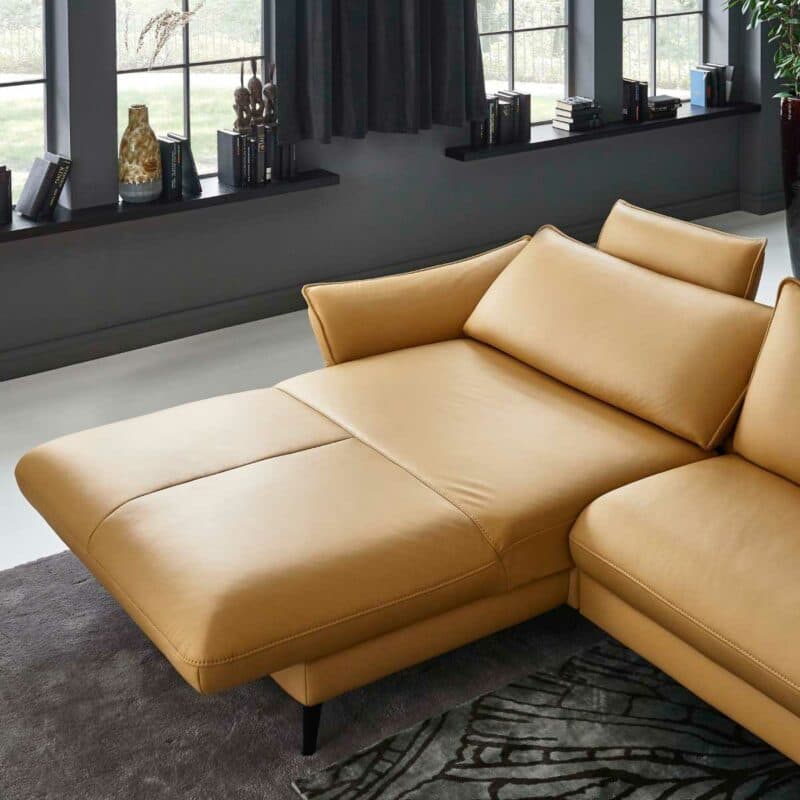 Couchliebe Houston Elementgruppe mit Lederbezug in Curry und Ottomane links als Wohnbeispiel mit Ansicht Relaxfunktion.
