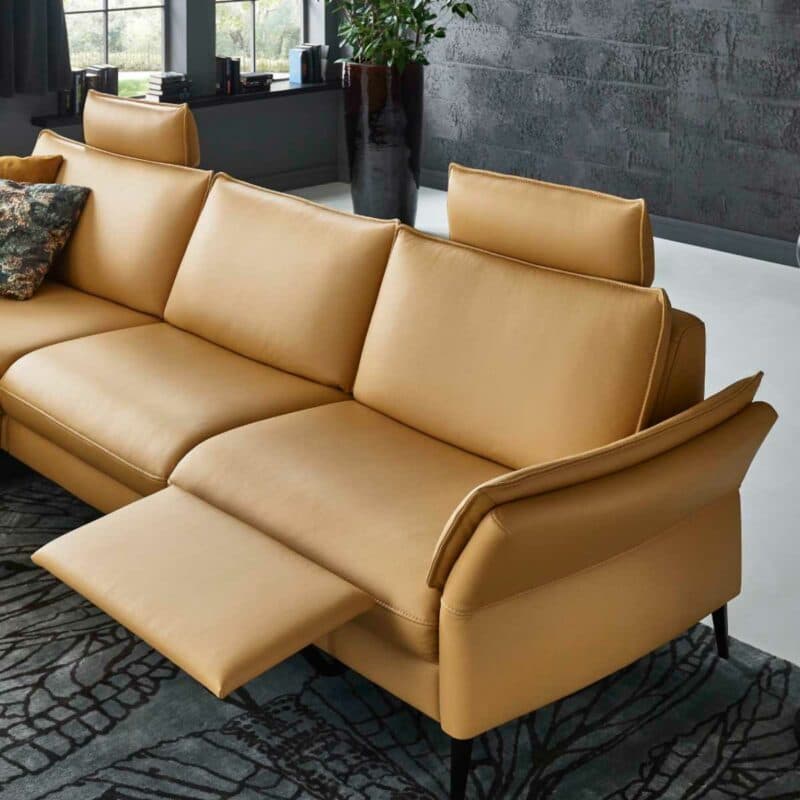 Couchliebe Houston Elementgruppe mit Lederbezug in Curry und Ottomane links als Wohnbeispiel mit Ansicht Relaxfunktion.
