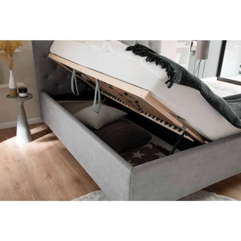 Trendstore San Remo Polsterbett mi Bettkasten in Hellgrau mit Füßen in Eiche mit hochgeklapptem Lattenrost in Detailansicht.