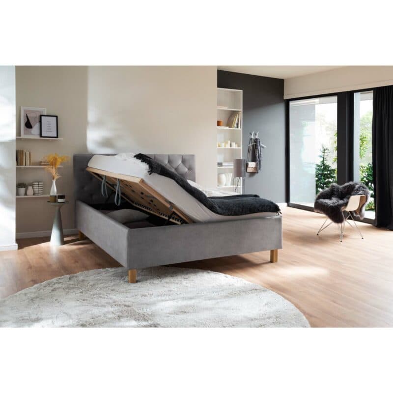 Trendstore San Remo Polsterbett mi Bettkasten in Hellgrau mit Füßen in Eiche mit hochgeklapptem Lattenrost als Wohnbeispiel.