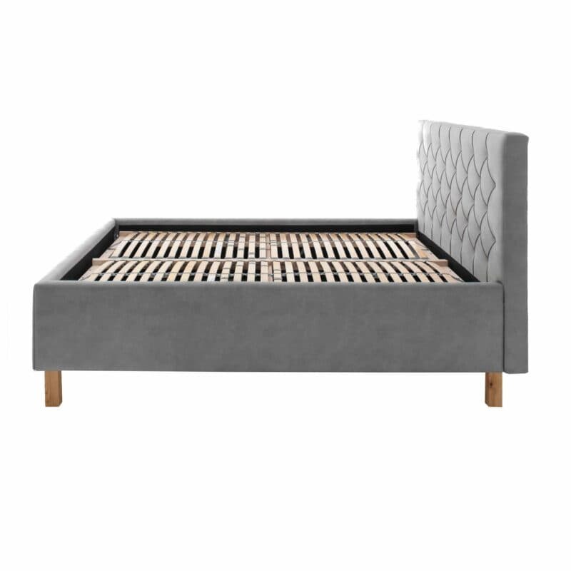 Trendstore San Remo Polsterbett mi Bettkasten in Hellgrau mit Füßen aus Eiche in seitlicher Ansicht.