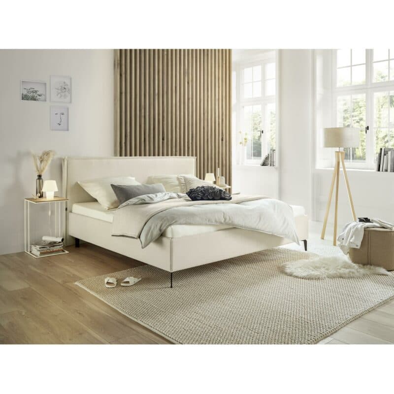 Musterring Elos Polsterbet mit Textilbezug JAB 9895 in Creme, Kopfteil mit Stehsaum und Metallfüßen als Wohnbeispiel.