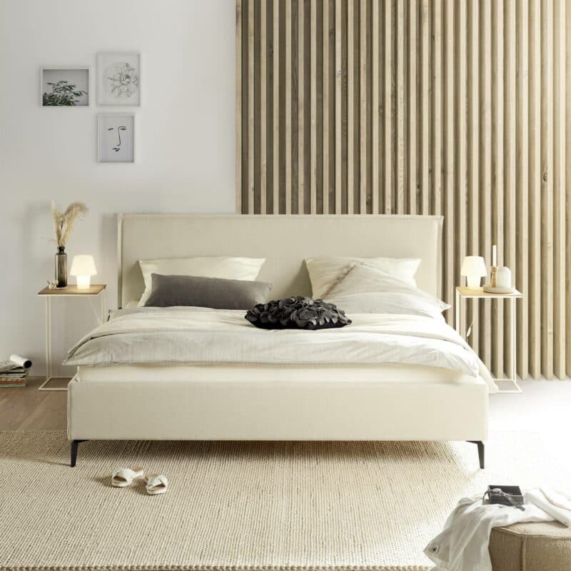 Musterring Elos Polsterbett mit Textilbezug JAB 9895 in Creme, Kopfteil mit Stehsaum und Metallfüßen als Wohnbeispiel in frontaler Ansicht.